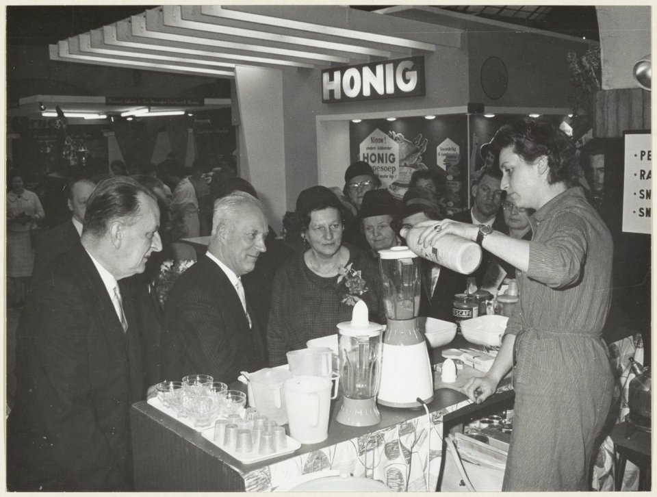 Voorjaarsbeurs in het Krelagehuis. Burgemeester Cremers en andere bezoekers bij de stand van de fa. Nestlé, fabrikant van Nescafe poederkoffie. NL-HlmNHA 54004474