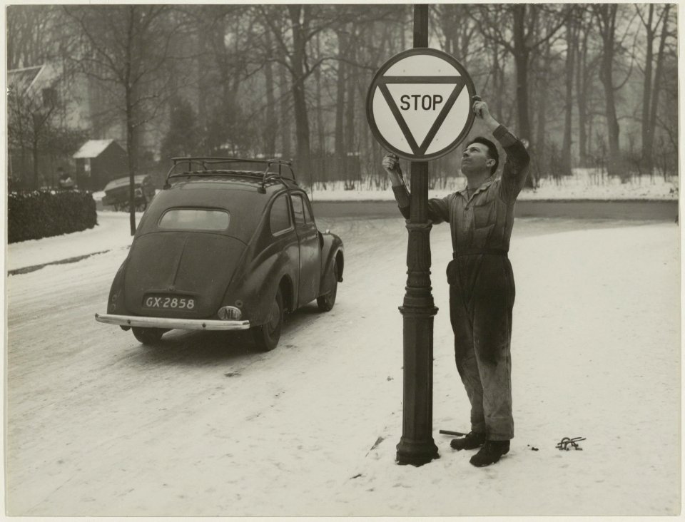 Voor het in werking treden van de nieuwe verkeerswet op 1 januari 1951, wordt op een onbekende locatie het nieuwe stopbord geplaatst. NL-HlmNHA 54010560
