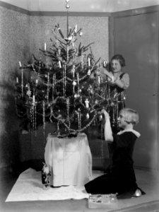 Vooraan zittend Renée en Hans bezig met het versieren kerstboom, Bestanddeelnr 189-1125