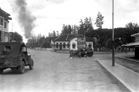 Voor een verkeersplein en kruising staat een artillerietrekker met geschut stil, Bestanddeelnr 5726