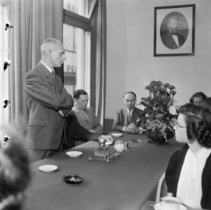 Warenhuis Bijeenkomst Een staande man (directeur) spreekt Aan de muur een po, Bestanddeelnr 900-5332