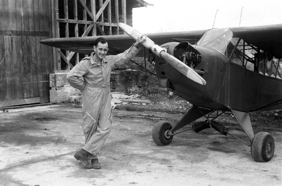 Vliegenier poseert bji Piper Cub L-4J Grashopper, Bestanddeelnr 5901