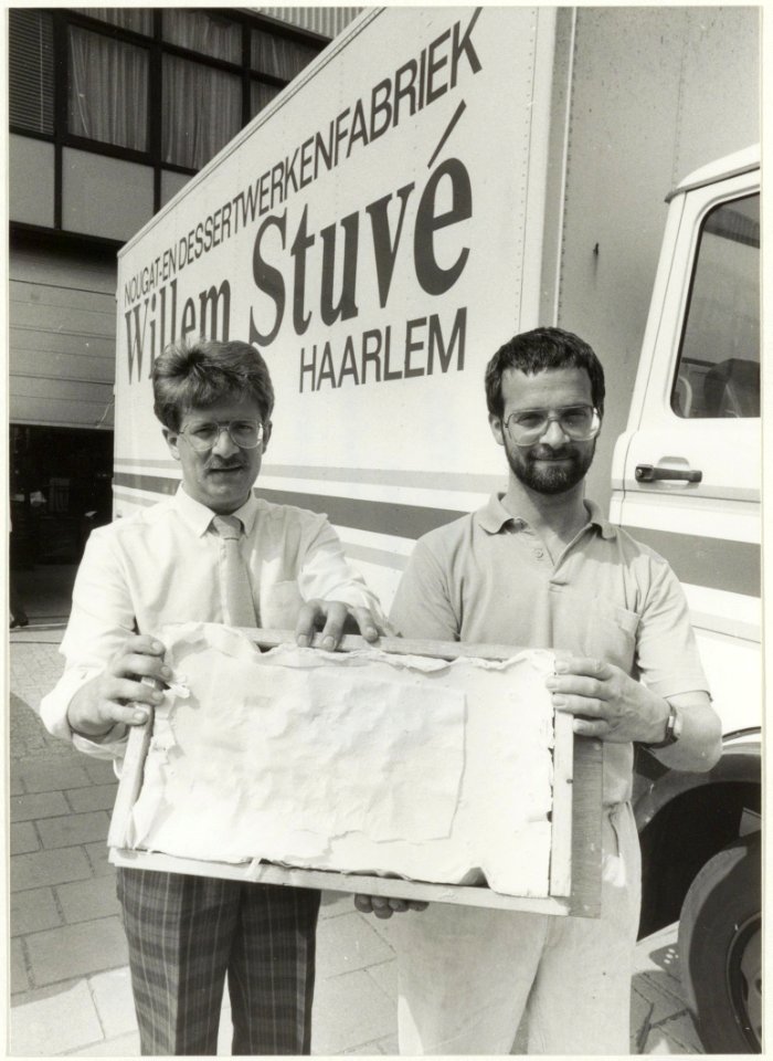Wim(l) en Frans de Zwart, eigenaars van zoetwarenfabriek Willem Stuvé met een enorme plak noga. NL-HlmNHA 54002627