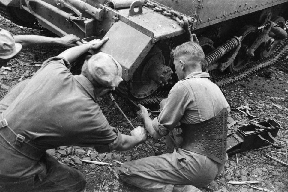 Werkzaamheden aan het loopwerk van een Universal Carrier. De man rechts draag ee, Bestanddeelnr 482-3-2