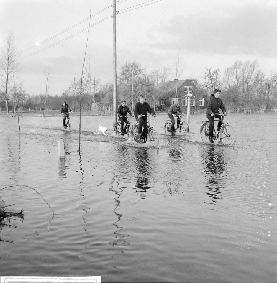 Wateroverlast in de Gelderse Vallei kinderen die door het water fietsen in Zwar, Bestanddeelnr 918-5499