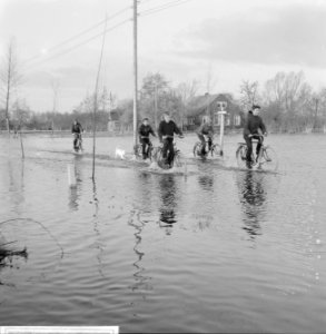 Wateroverlast in de Gelderse Vallei kinderen die door het water fietsen in Zwar, Bestanddeelnr 918-5499