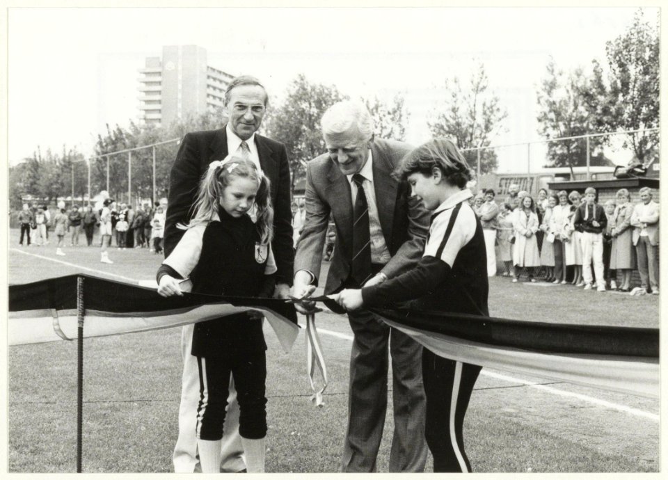 Wethouder Piet Sikma knipt het lint door tijdens de officiële opening van het nieuwe softbalveld. Op de foto v.l.n.r. Wendy Schavemaker, Joop Bakker, Piet Sikma en Evelyn van Dongen. NL-HlmNHA 54016563