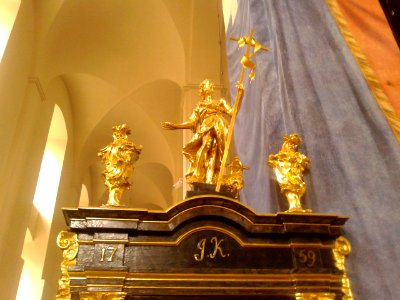 Złote figurki nad wejściem do schodów na ambonę