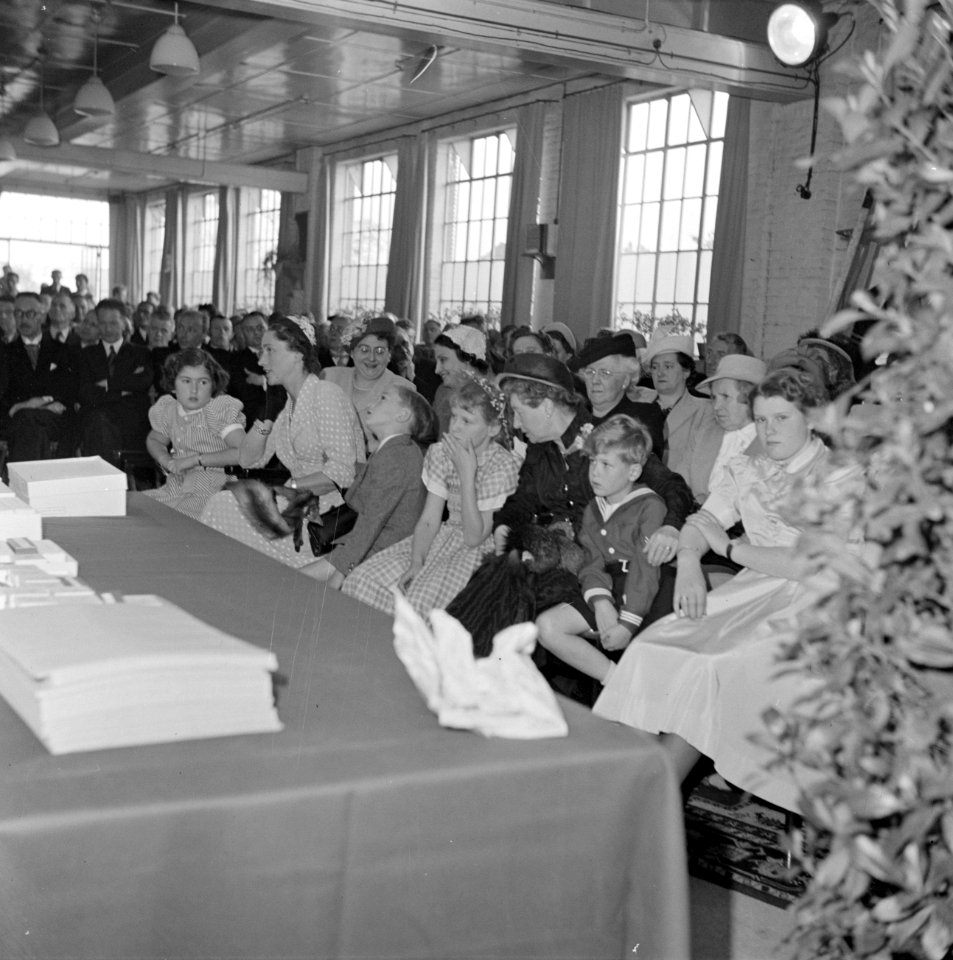 Zaal met zittende mensen, de vrouwen en de kinderen gescheiden van de mannen, Bestanddeelnr 255-8517