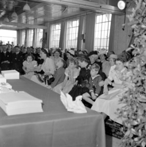 Zaal met zittende mensen, de vrouwen en de kinderen gescheiden van de mannen, Bestanddeelnr 255-8517