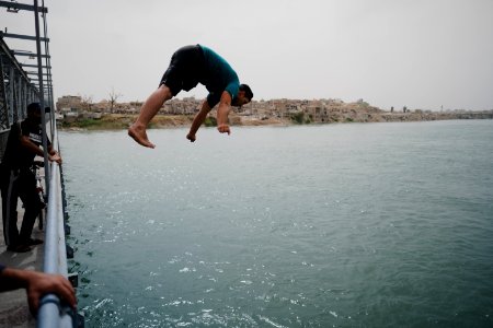 Young men gathered at Mosul's "Old Bridge" over the Tigris River in summer of 2019 to jump into the water and escape summer heat 14