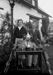 Young couple with golf clubs and three trophies (1294064)