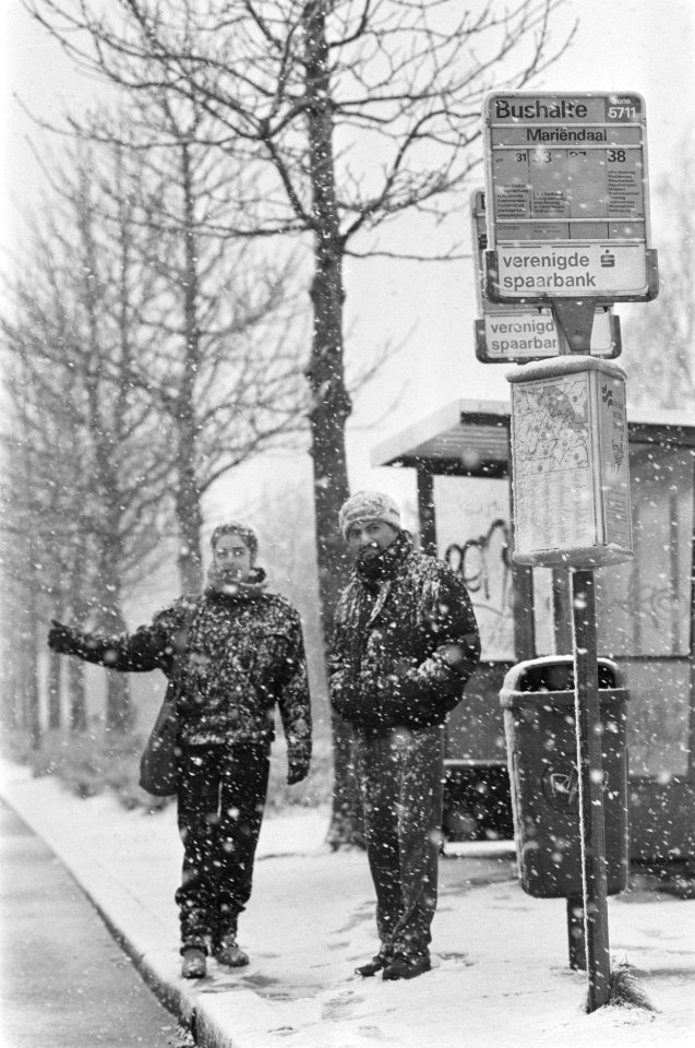 Zitten in de sneeuw bij een bushalte in Amsterdam in verband met staking openbaa, Bestanddeelnr 933-9285