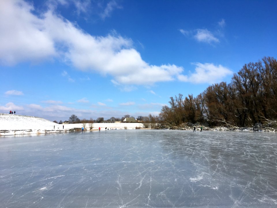 Winters rivierlandschap met schaatsers