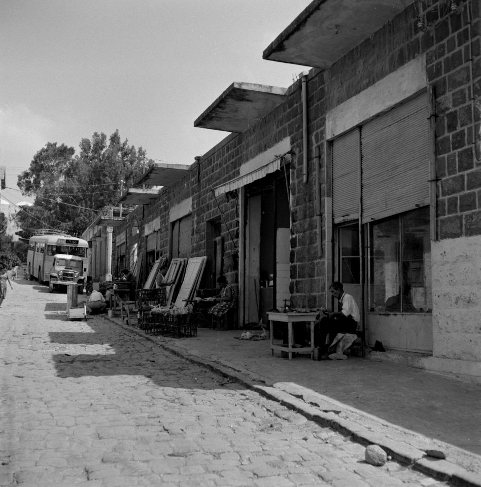 Winkels en werkplaatsen in een straat in Tiberias met een geparkeerde autobus …, Bestanddeelnr 255-4080