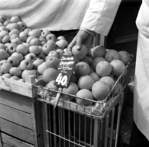 Winkelier met een Duitse sinaasappel in de hand bij zijn winkel in Bad Mergenthe, Bestanddeelnr 254-3226