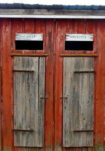 Wooden outhouse with texts MEN and WOMEN in Finnish