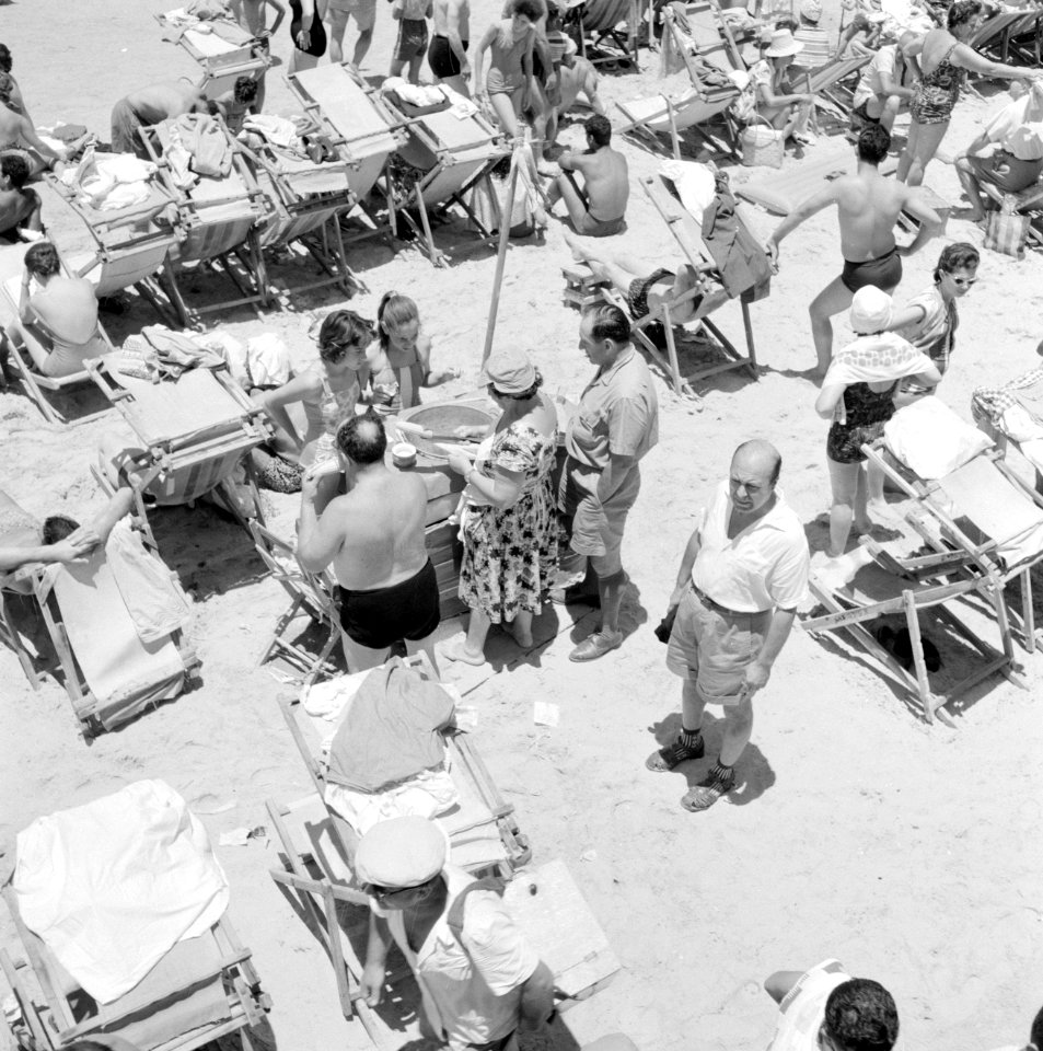 Badgasten in strandstoelen, in het midden een verkoopster die maïskolven staat t, Bestanddeelnr 255-1976