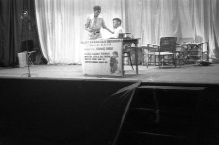 Cabaret voorstelling. Twee Indonesische mannen bij een tafel. Een zit achter de , Bestanddeelnr 6175