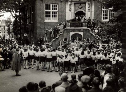 Burgemeester H.M. van Fenema opent vanaf het bordes van het raadhuis de sportweek. Aangekocht in 1977 van fotograaf C. de Boer. Identificatienummer 54-004039, NL-HlmNHA 54004039