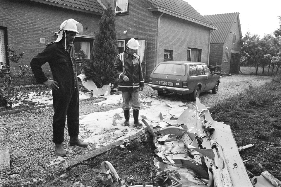 Brandweerlieden kijken naar resten F15 brandstoftank die neerstortte bij Ingen , Bestanddeelnr 933-6904