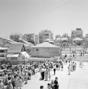 Zomers geklede mensen lopen over een plein dat toegang geeft tot het strand, Bestanddeelnr 255-1938