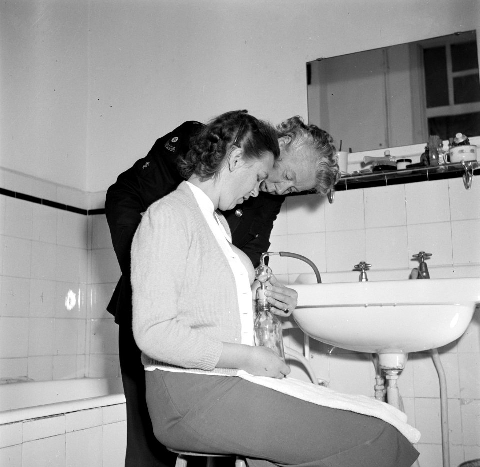 Zuster M.G. Niemeyer assisteert mevrouw Rietveld bij het kolven met behulp van d, Bestanddeelnr 254-2487