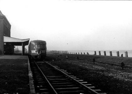HUA-153284-Afbeelding van een diesel-electrisch treinstel DE 1 ("Blauwe Engel") van de N.S. langs het perron van het station Stavoren te Stavoren met links het oude stationsgebouw kort voor de afbraak en rechts 