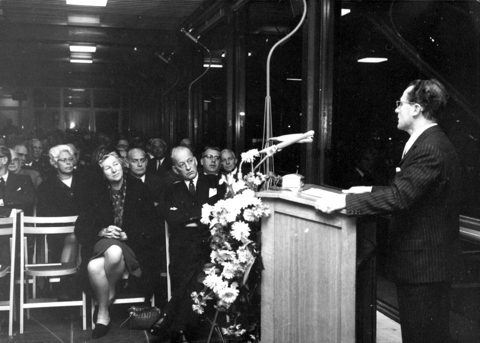 HUA-154491-Afbeelding van mr. M.G. de Bruin, president-directeur van de N.S., tijdens een toespraak bij de opening van de Traverse van het N.S.-station Utrecht C.S. te Utrecht. Op de eerste rij zitten de heer en