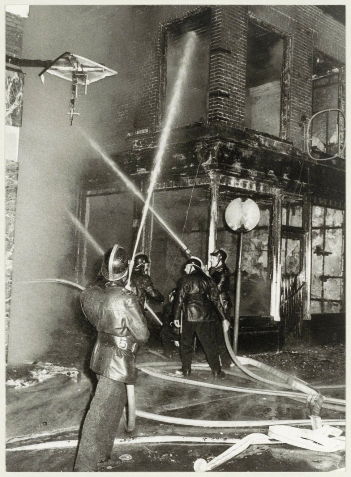 Het blussen van brand in de Paarlaarsteeg, hoek Koningstraat. Bij de brand gingen 2 café's verloren, in de Paarlaarsteeg Piet in de Ton en op de hoek de Horse Club bar. NL-HlmNHA 54003417