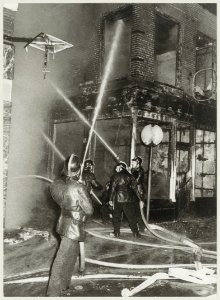 Het blussen van brand in de Paarlaarsteeg, hoek Koningstraat. Bij de brand gingen 2 café's verloren, in de Paarlaarsteeg Piet in de Ton en op de hoek de Horse Club bar. NL-HlmNHA 54003417