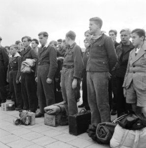 Jongens staan aangetreden met bagage, sommige in een soort uniform, Bestanddeelnr 900-9823