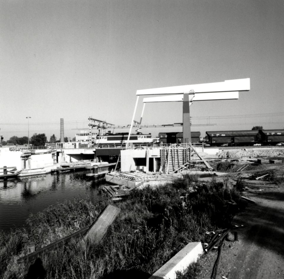 HUA-170416-Gezicht op de nieuwe spoorbrug over de Vecht te Weesp, met een goederentrein getrokken door de electrische locomotief nr. 1606 (serie 1600) van de N.S. Voor de brug is men bezig met de bouw van de twe