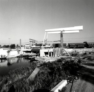 HUA-170416-Gezicht op de nieuwe spoorbrug over de Vecht te Weesp, met een goederentrein getrokken door de electrische locomotief nr. 1606 (serie 1600) van de N.S. Voor de brug is men bezig met de bouw van de twe