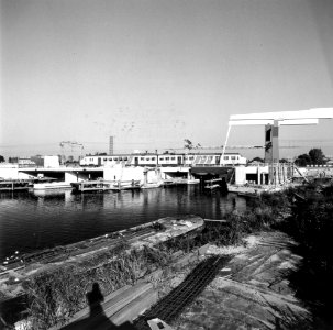 HUA-170415-Gezicht op de nieuwe spoorbrug over de Vecht te Weesp, met een electrisch treinstel plan V (mat. 1964) van de N.S. Voor de brug is men bezig met de bouw van de tweede, nieuwe brug