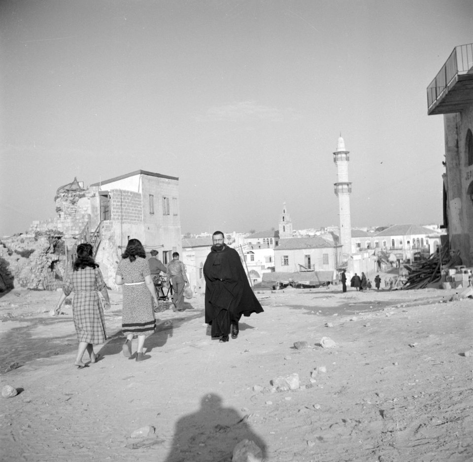 Jaffa. Wandelaars, onder wie een christelijke geestelijke, op straat met op de …, Bestanddeelnr 255-0076