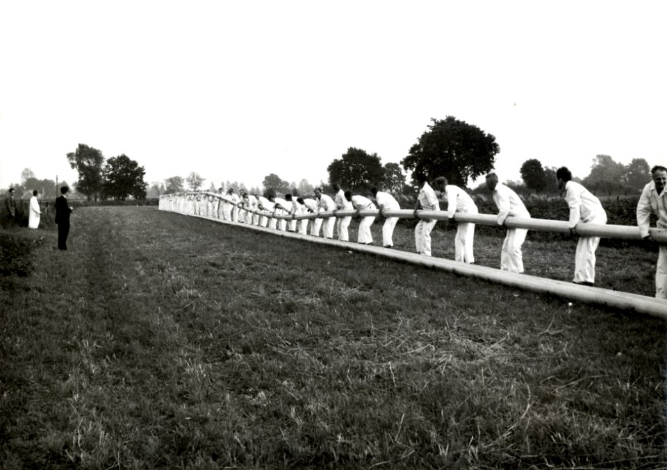 HUA-171257-Afbeelding van medewerkers van de firma Wavin te Hardenberg die drie 110 meter lange plastic buizen naar het station brengen voor transport naar Rotte