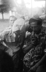 Luitenant in camouflage uniform spreekt door een microfoon. Naast hem een adjuda, Bestanddeelnr 10752
