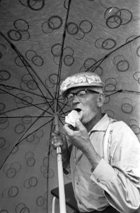 Koopman op Waterlooplein eet ijsje onder parasol, Bestanddeelnr 921-4799