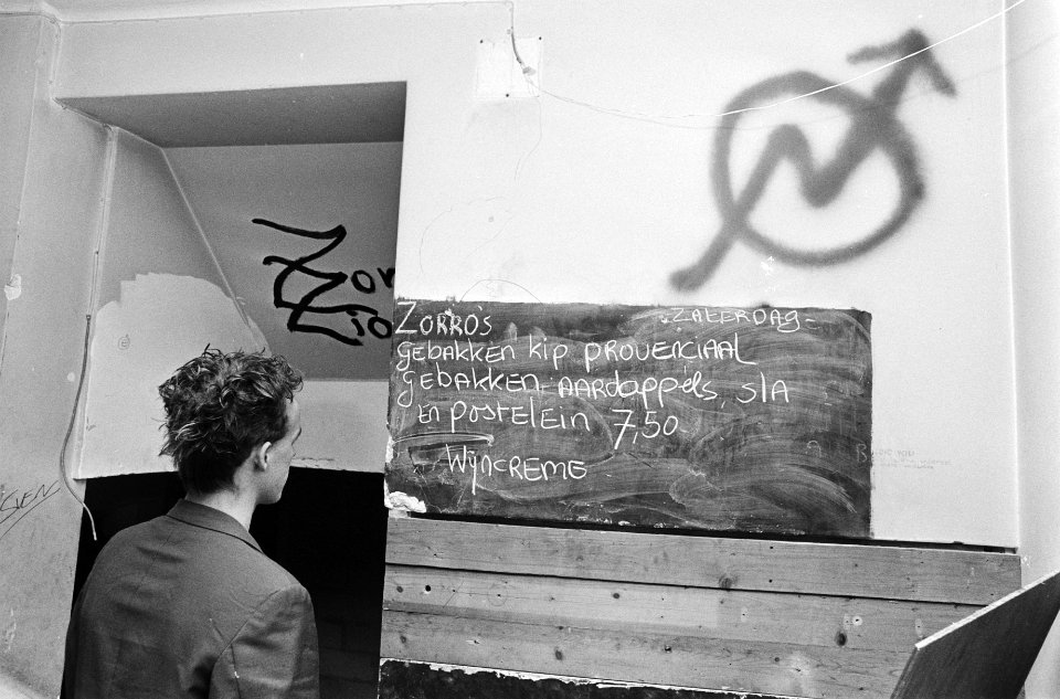 Krakerssymbool op de muur en daaronder een bord met een menu, Bestanddeelnr 932-6680