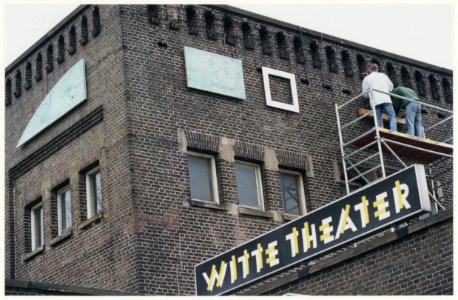 Kunstenaar Pieter Kooistra bevestigd een ornament van zijn kunstwerk aan de gevel van het Witte Theater in IJmuiden. NL-HlmNHA 54050081 photo