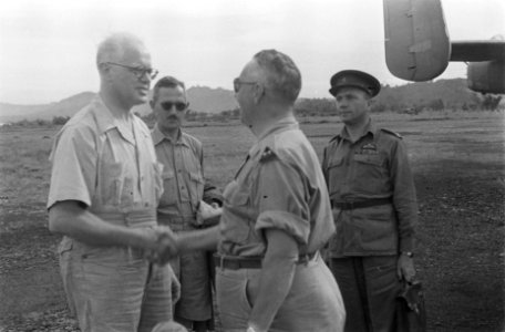 Dr. C.P.M. Romme in licht overhemd, schudt op een vliegveld de hand van een lui…, Bestanddeelnr 138-3-6