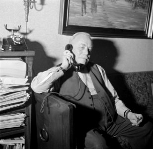 Dirk Nak telefonerend op de bank in zijn woonkamer, Bestanddeelnr 252-9016
