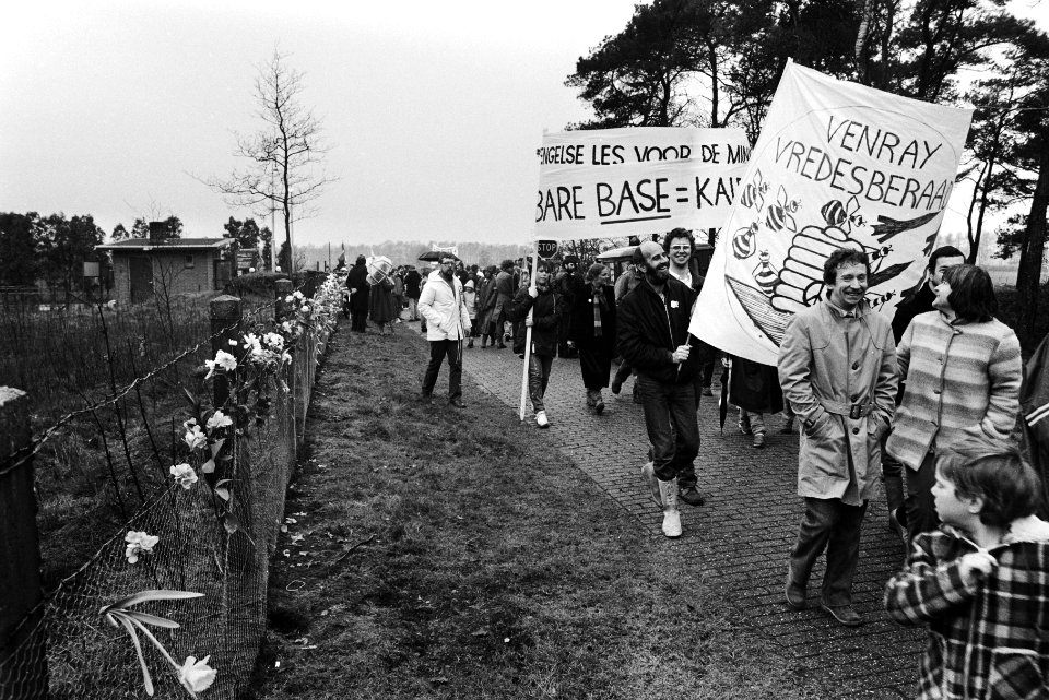 Demonstranten met spandoeken lopen langs de ingang van de basis, Bestanddeelnr 932-5374