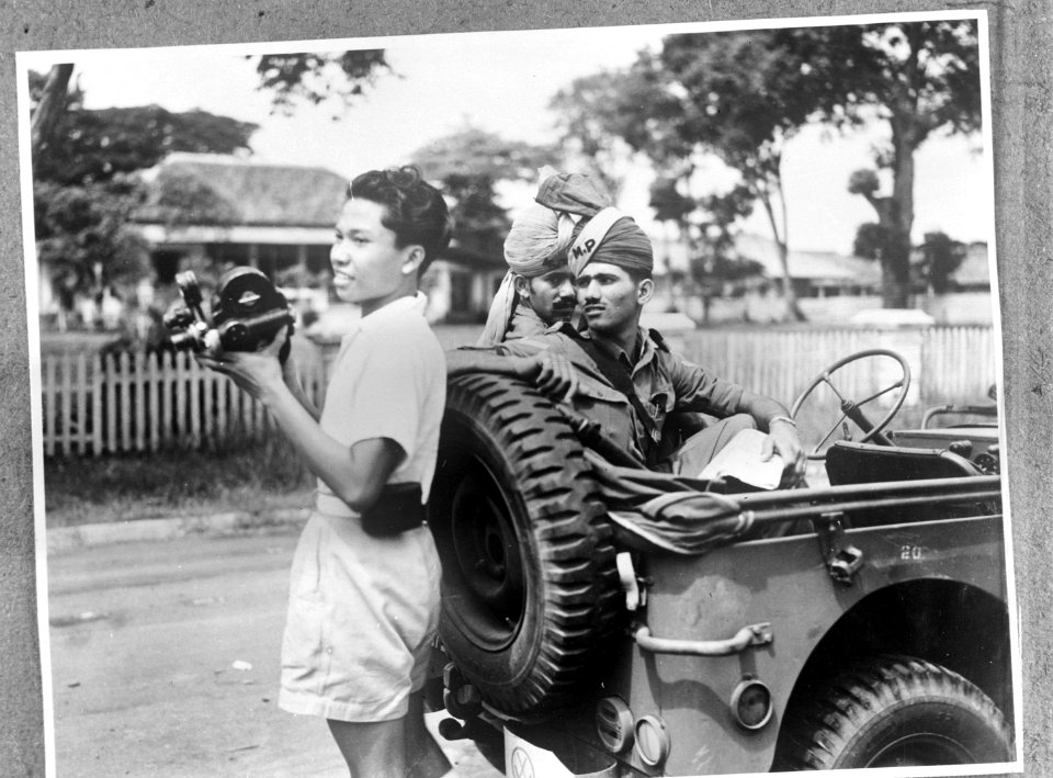 Een Indonesische jonge man met filmcamera. Achter hem twee Brits-Indische milita, Bestanddeelnr 935-3394