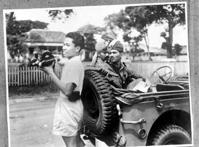 Een Indonesische jonge man met filmcamera. Achter hem twee Brits-Indische milita, Bestanddeelnr 935-3394