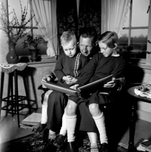 Gerard met zijn beide kinderen op schoot terwijl ze een fotoalbum bekijken. Link, Bestanddeelnr 254-3311