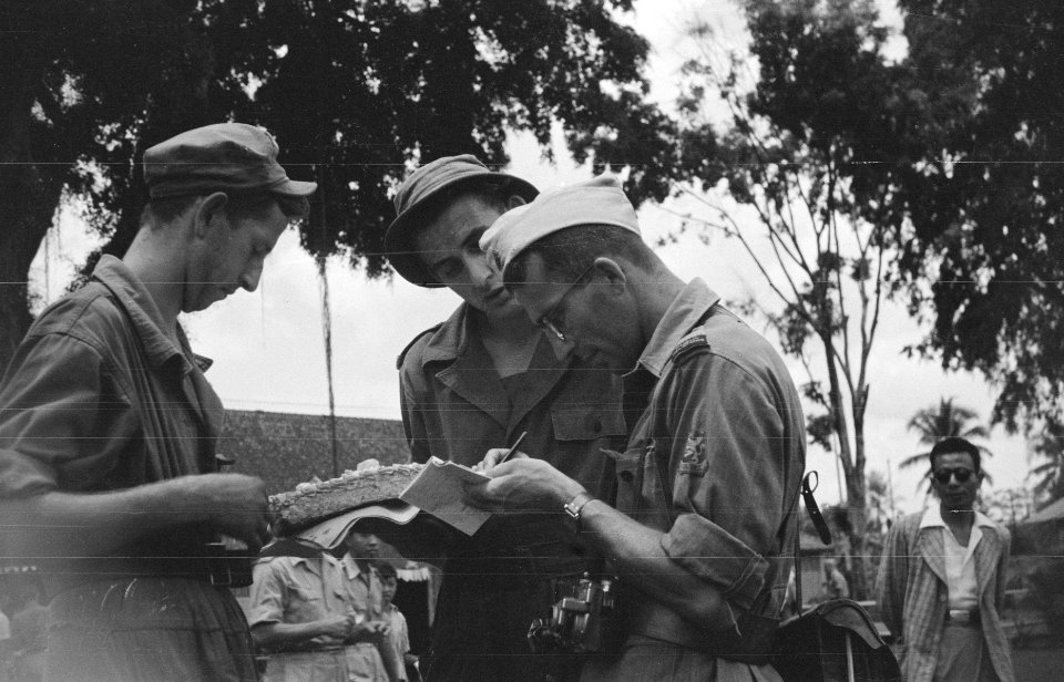 Drie militairen. Een schrijft iets op in een notttieboekje. De ander heeft een , Bestanddeelnr 378-3-3