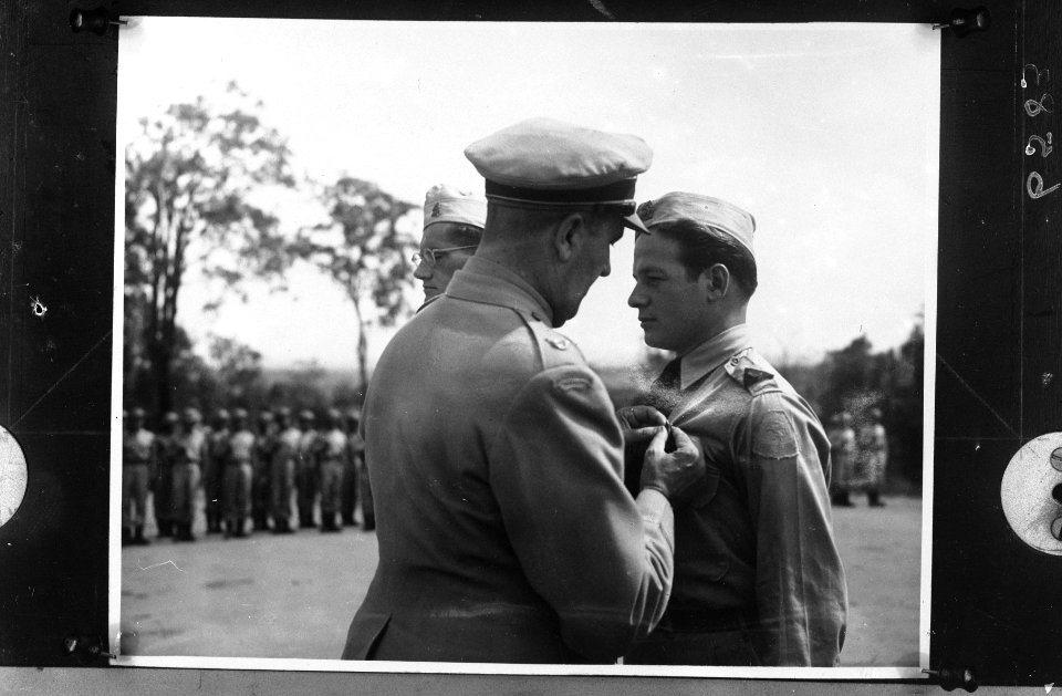 Een hoge officier speldt een militair een onderscheiding op, Bestanddeelnr 900-6583