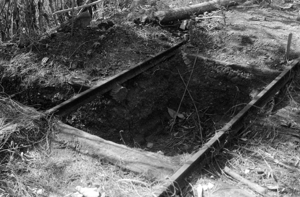 Een gegraven gat tussen de rails van een in onbruik geraakte spoorbaan, Bestanddeelnr 1306